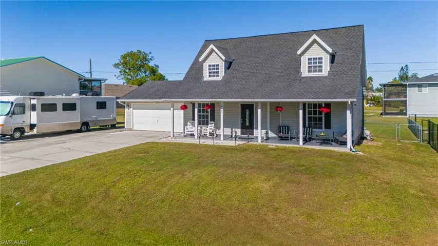 Cape cod house featuring covered porch, a garage, and a front lawn