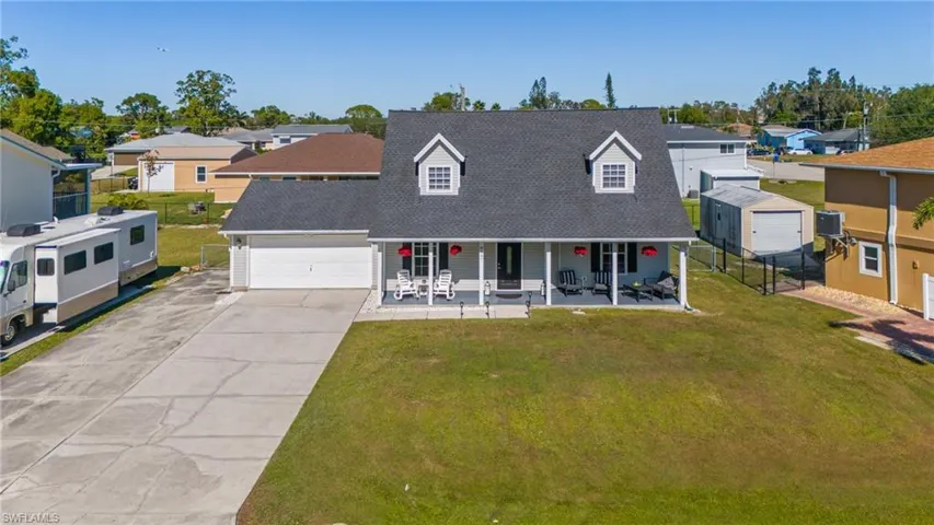 View of front of property with central AC unit, a garage, covered porch, and a front lawn
