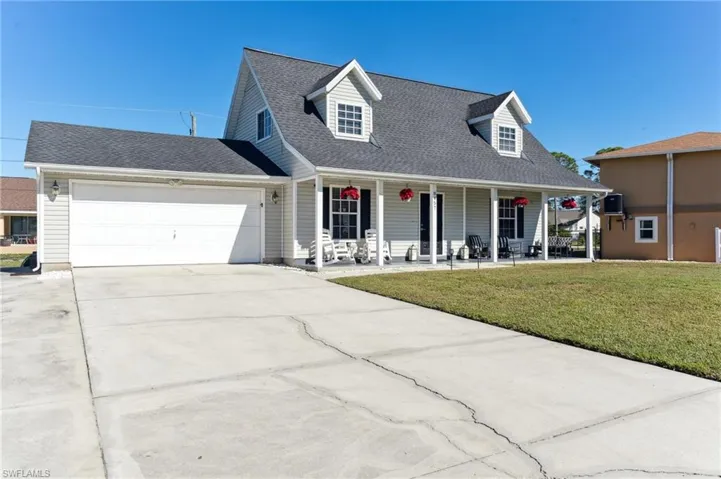 Cape cod-style house with a garage, covered porch, and a front yard