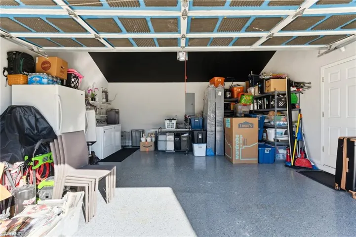 Garage with electric panel, white fridge, and independent washer and dryer