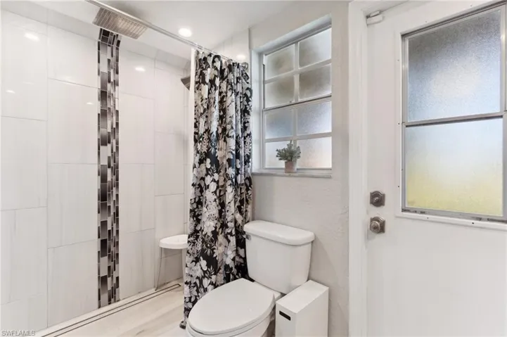 Bathroom with hardwood / wood-style floors, toilet, and a shower with curtain