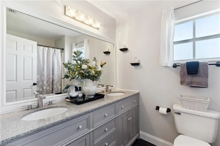 Bathroom with vanity, toilet, and plenty of natural light