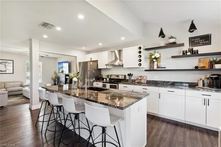 Kitchen featuring stainless steel appliances, a kitchen island with sink, and wall chimney exhaust hood