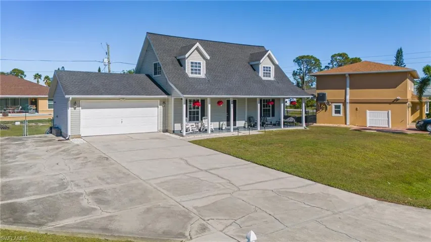 New england style home with covered porch, a garage, and a front yard