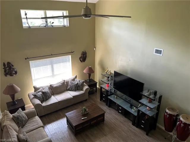 Living room featuring a wealth of natural light, ceiling fan, and dark wood-type flooring
