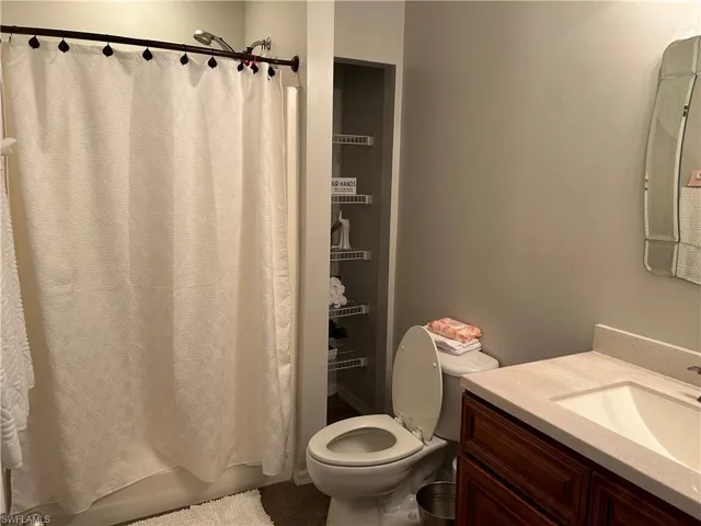 Full bathroom with vanity, shower / bath combo with shower curtain, and toilet