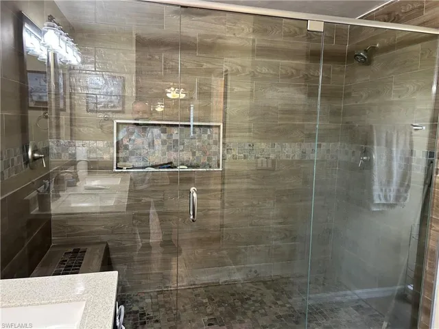 Bathroom featuring a shower with shower door and vanity