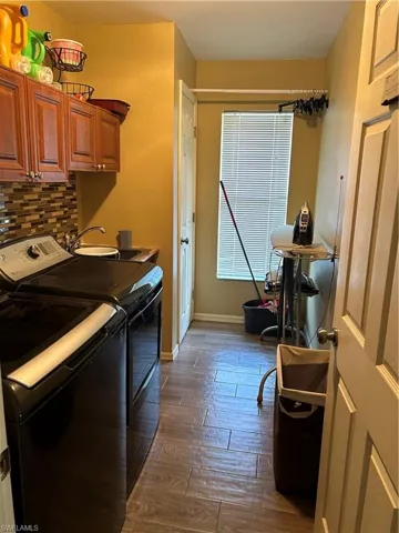 Laundry area with separate washer and dryer, cabinets, dark hardwood / wood-style floors, and sink