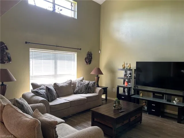 Living room featuring a high ceiling, dark wood-type flooring, and a healthy amount of sunlight