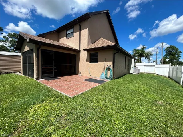 Rear view of property with a sunroom, cooling unit, a patio area, and a lawn