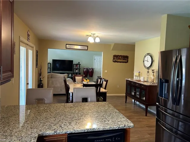 Kitchen with stainless steel fridge, light stone countertops, and dark wood-type flooring
