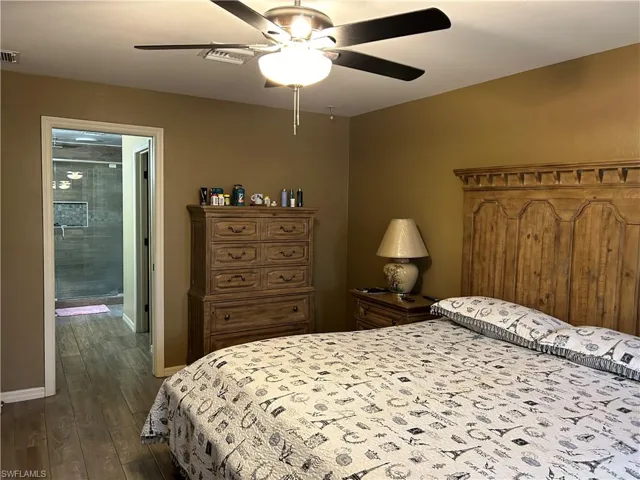 Bedroom with ensuite bath, ceiling fan, and hardwood / wood-style floors
