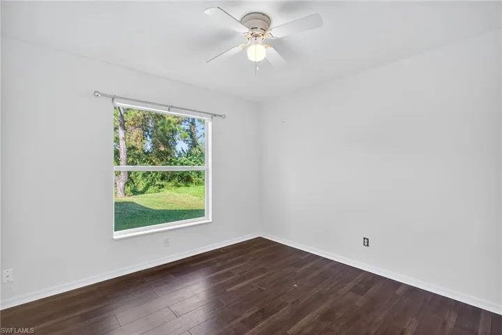Spare room with dark wood-type flooring and ceiling fan