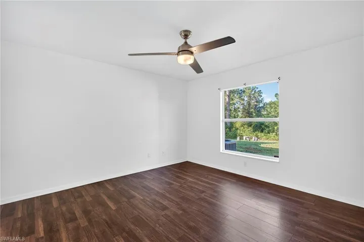 Unfurnished room featuring dark wood-style floors and a ceiling fan