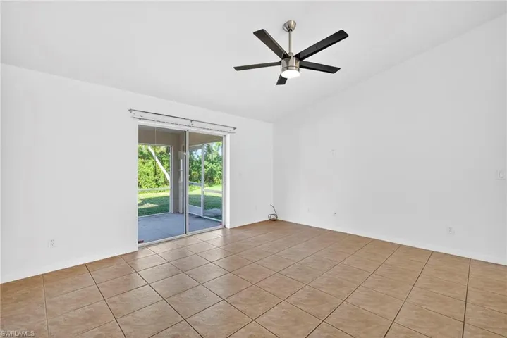 Empty room featuring lofted ceiling, tile patterned floors, and ceiling fan