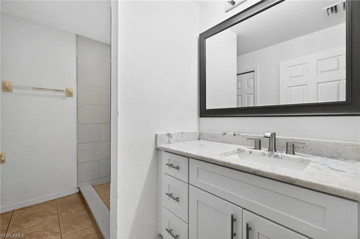 Full bath with vanity, light tile patterned floors, and tiled shower