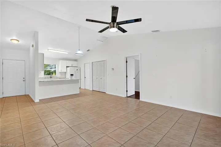 Unfurnished living room with lofted ceiling, light tile patterned floors, and ceiling fan
