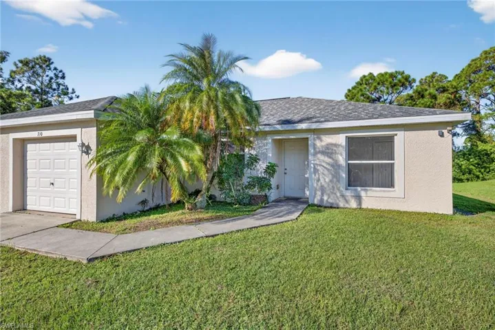 Single story home with a garage, a front yard, and stucco siding