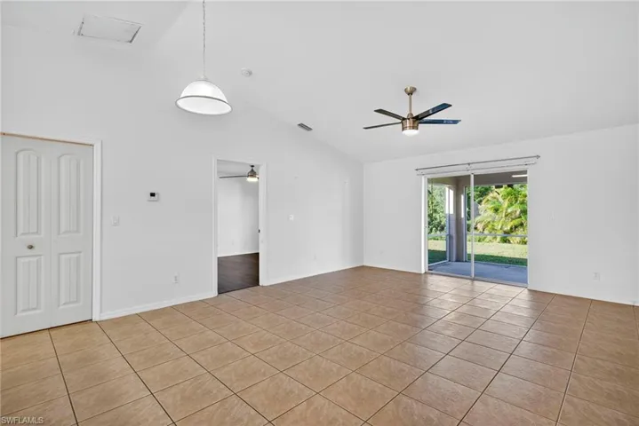 Spare room featuring light tile patterned flooring, ceiling fan, and high vaulted ceiling