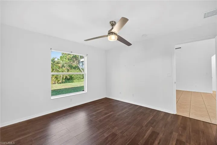 Unfurnished room with dark wood-style floors and ceiling fan