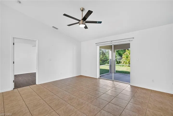 Spare room featuring lofted ceiling, tile patterned flooring, and ceiling fan