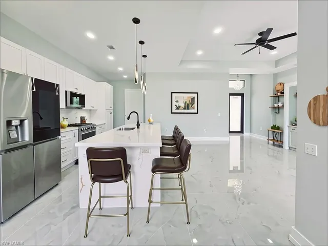 Kitchen with appliances with stainless steel finishes, light marble finish floors, recessed lighting, white cabinetry, and light countertops