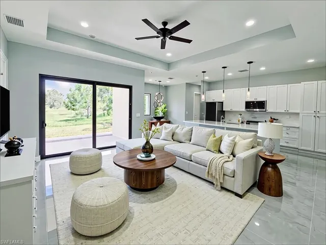 Living area featuring a tray ceiling, recessed lighting, and ceiling fan