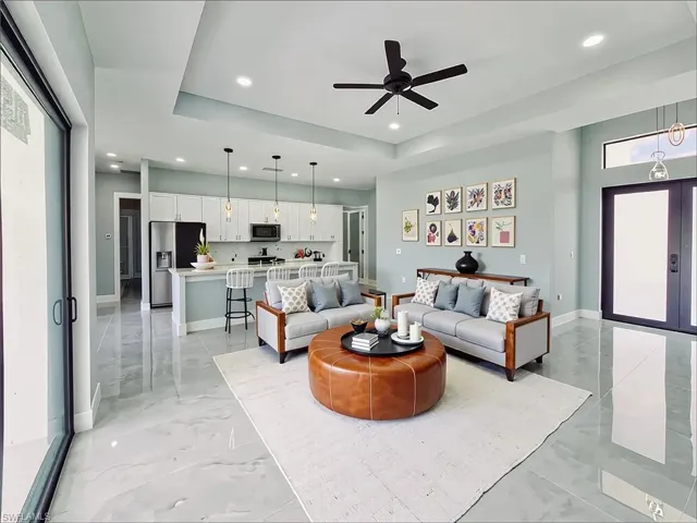 Living room featuring recessed lighting, ceiling fan, a raised ceiling, and light marble finish floors