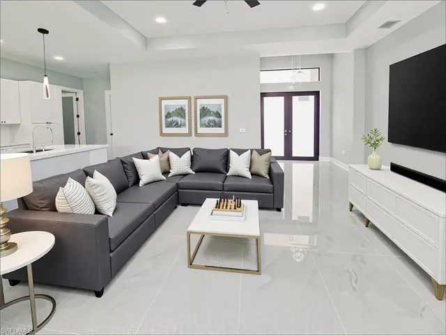 Living area featuring a raised ceiling, recessed lighting, ceiling fan, and french doors