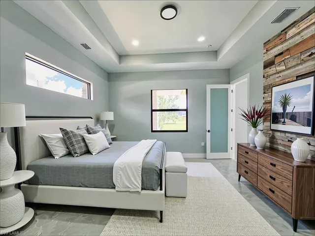 Bedroom with light marble finish flooring, a tray ceiling, recessed lighting, and wooden walls