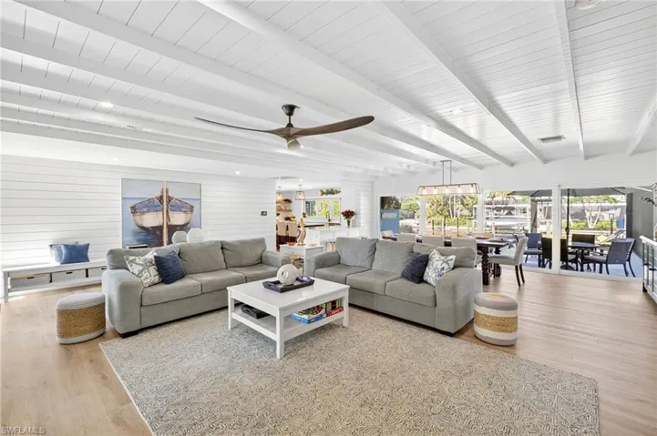 Living room with wood finished floors, a wood ceiling with exposed beams, and a ceiling fan