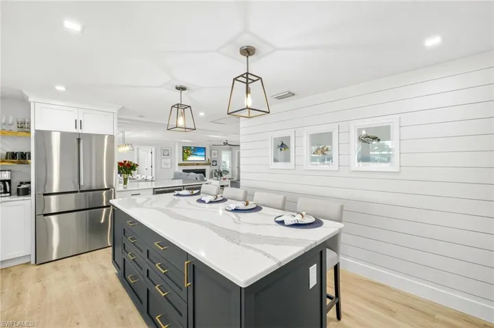 Kitchen with freestanding refrigerator, white cabinetry, light wood-type flooring, a center island, and hanging light fixtures
