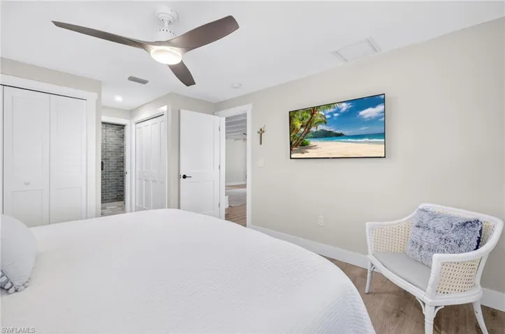 Bedroom featuring multiple closets, wood finished floors, and ceiling fan