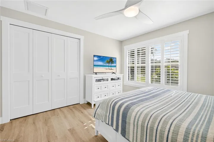 Bedroom with light wood finished floors, ceiling fan, and a closet