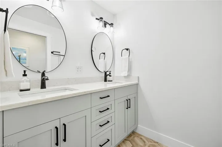 Full bathroom featuring double vanity and baseboards