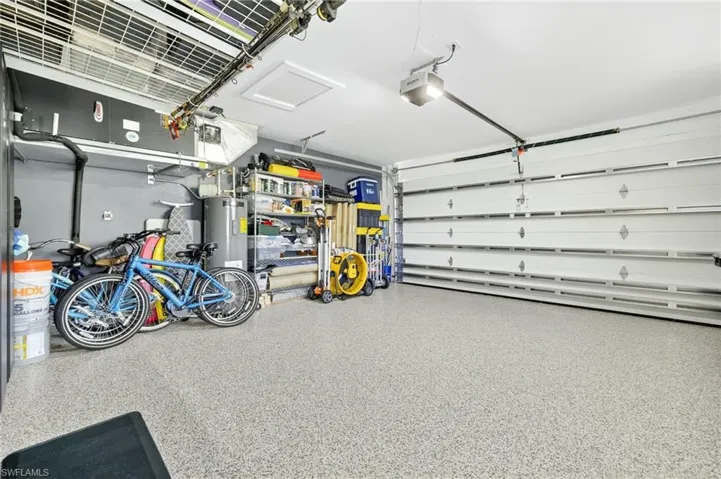 Garage featuring electric water heater and a garage door opener