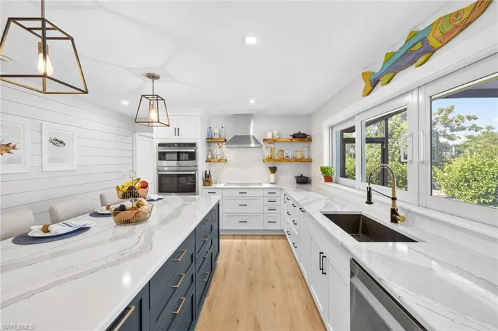 Kitchen featuring open shelves, light wood finished floors, white cabinetry, hanging light fixtures, and stainless steel appliances