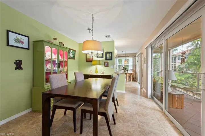 Dining space featuring light tile patterned floors, hurricane impact sliders and baseboards
