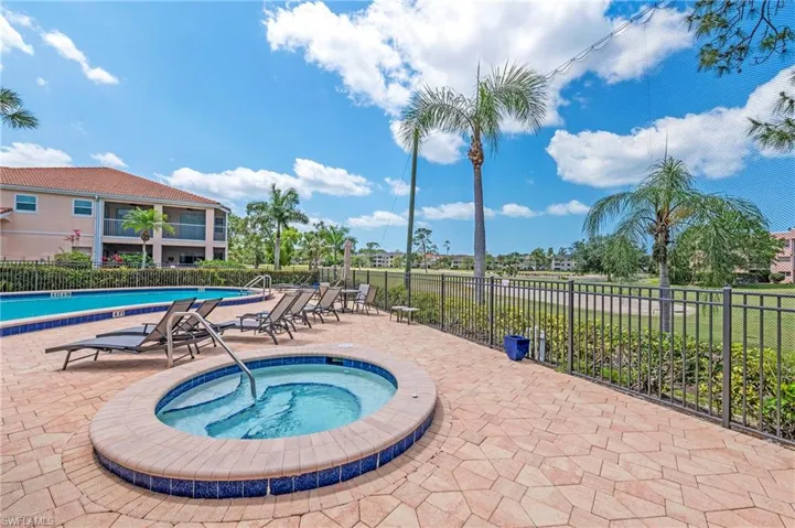 Community pool with a hot tub, a patio, and fence