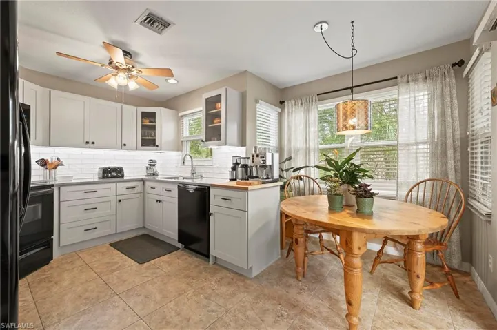 Kitchen & breakfast nook, featuring visible vents, plenty of natural light, ceiling fan, decorative backsplash, and black appliances