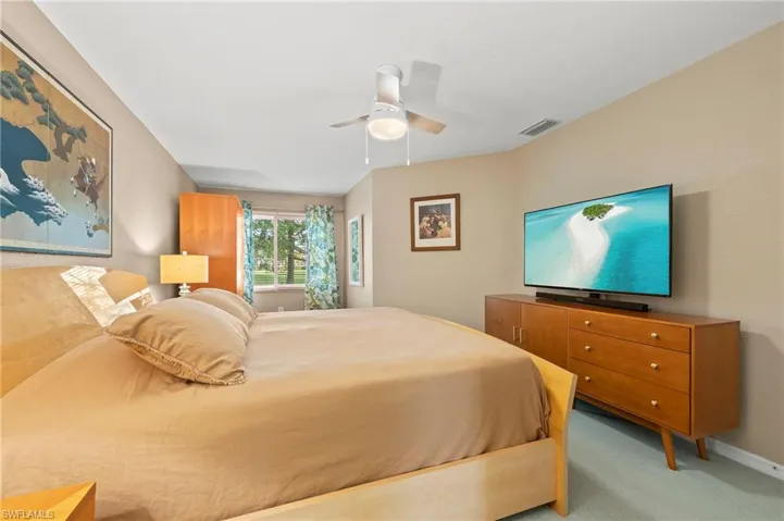 Bedroom with a ceiling fan, light colored carpet and baseboards