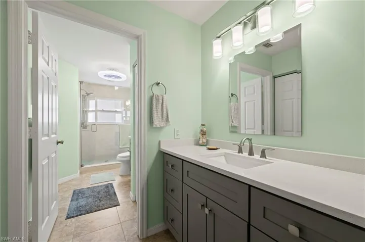 2nd sink/vanity area leading to full bath featuring toilet, a shower stall, tile patterned flooring, baseboards, and vanity