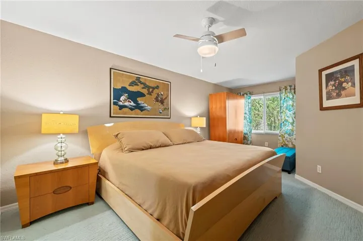 Bedroom with light carpet, a ceiling fan, and baseboards