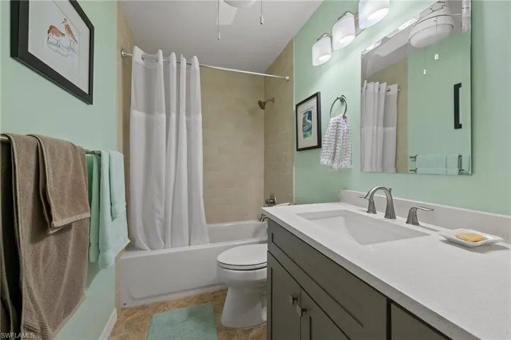 Bathroom with vanity, toilet, a ceiling fan, and shower/tub combo