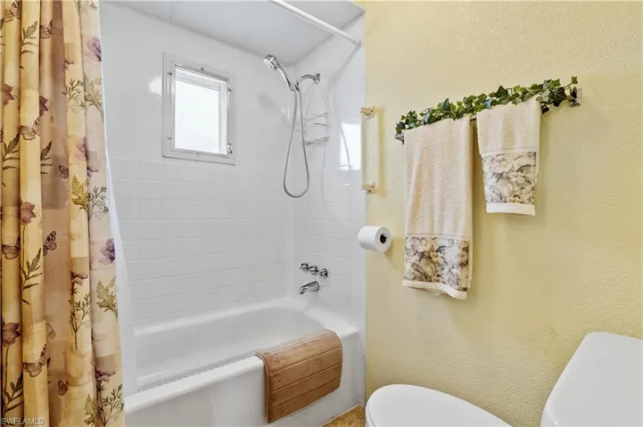 Bathroom with shower / tub combo with curtain and a textured wall