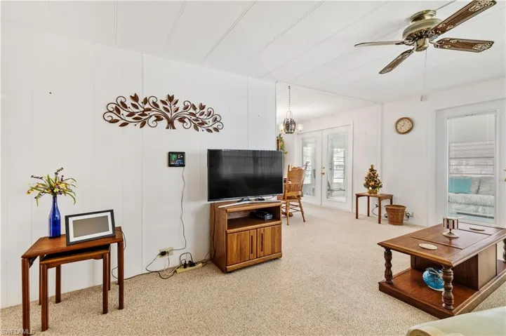 Living area with light carpet, ceiling fan, and hanging lights