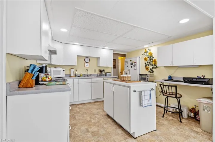 Kitchen with white cabinets, a center island, white appliances, light countertops, and recessed lighting