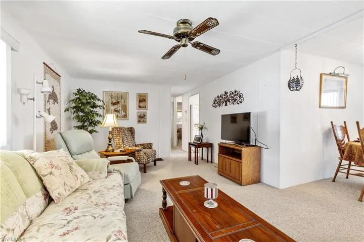 Living area featuring light carpet and a ceiling fan