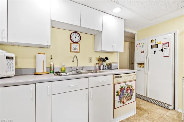 Kitchen featuring white appliances, white cabinetry, light countertops, and light flooring