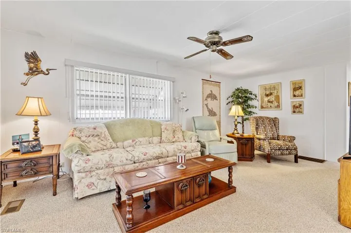 Living area with light colored carpet and a ceiling fan